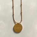 Gold necklace with a round pendant on a light gray background